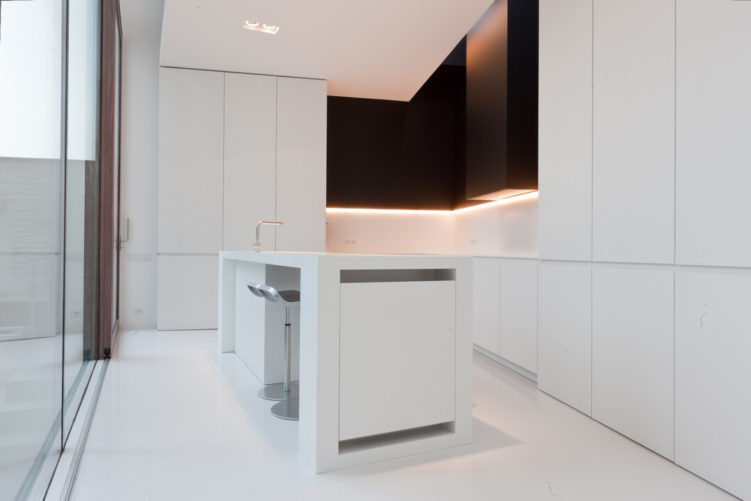Deze prachtige eiland keuken door WoonProject op maat gemaakt en ontworpen is afgewerkt met wit laminaat met Corian (kunststof) werkblad zonder naad.